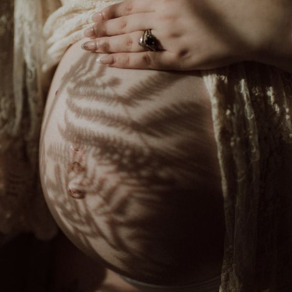 Close-up of a pregnant woman's hands resting on her belly.